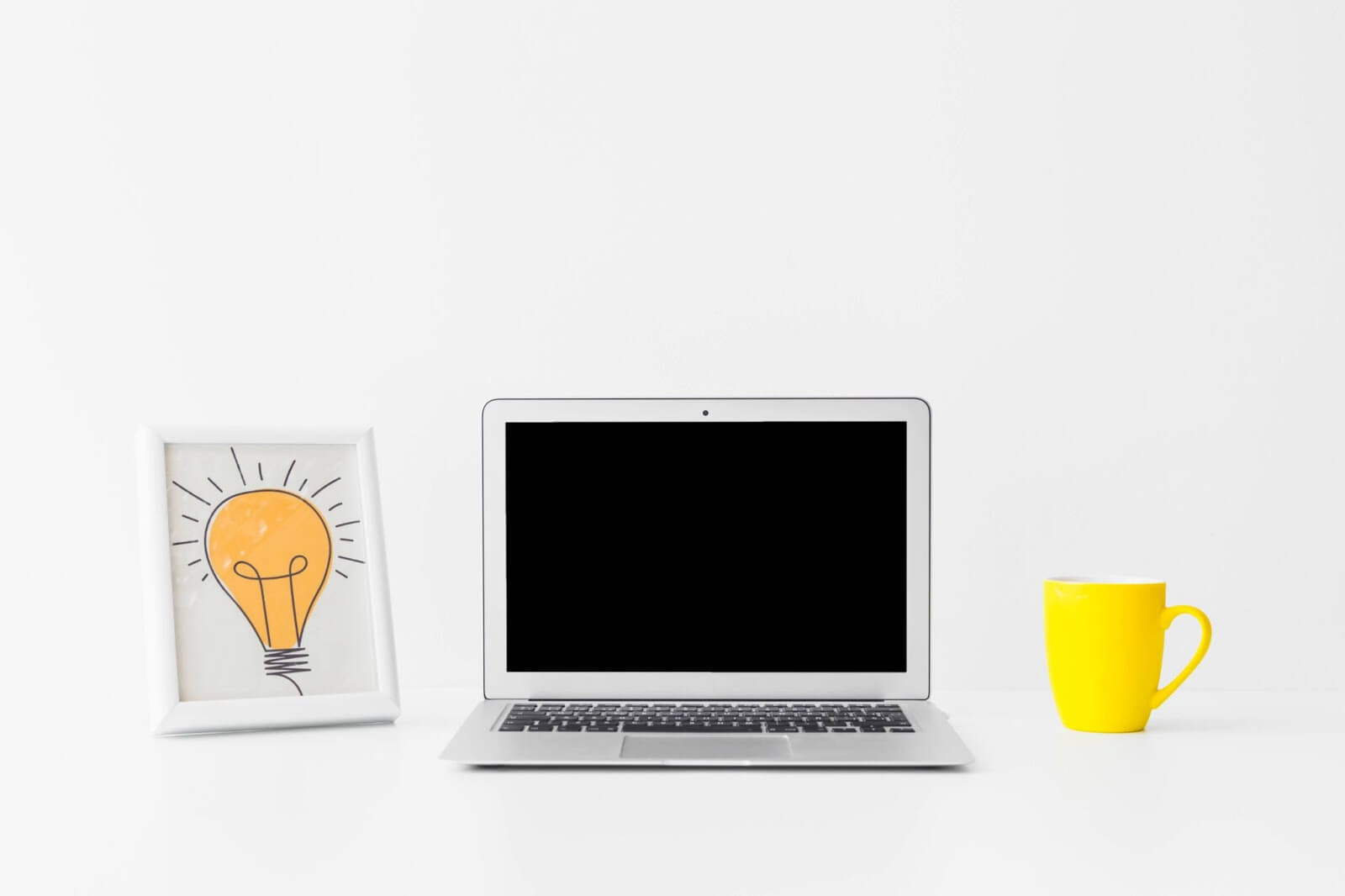 Symbolbild für Bilder SEO mit einem Laptop und Bilderrahmen mit einer Glühbirne als Assoziation für eine Idee.